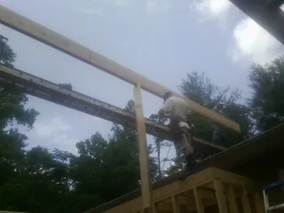Carpenter setting a ridge beam over a new addition frame — Ice Dam Removal by Roofing Brothers in Palmer